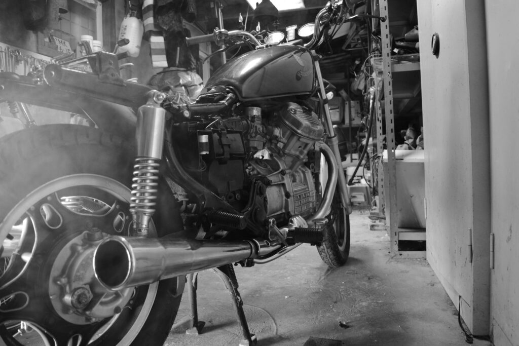 Classic motorcycle captured in monochrome inside a cluttered workshop.