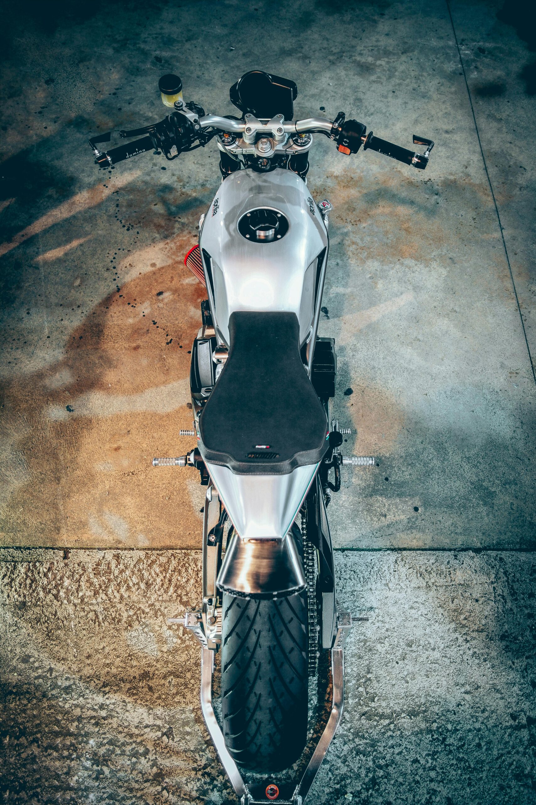 Aerial view of a sleek motorcycle parked on a concrete ground, showcasing its design and wheel structure.