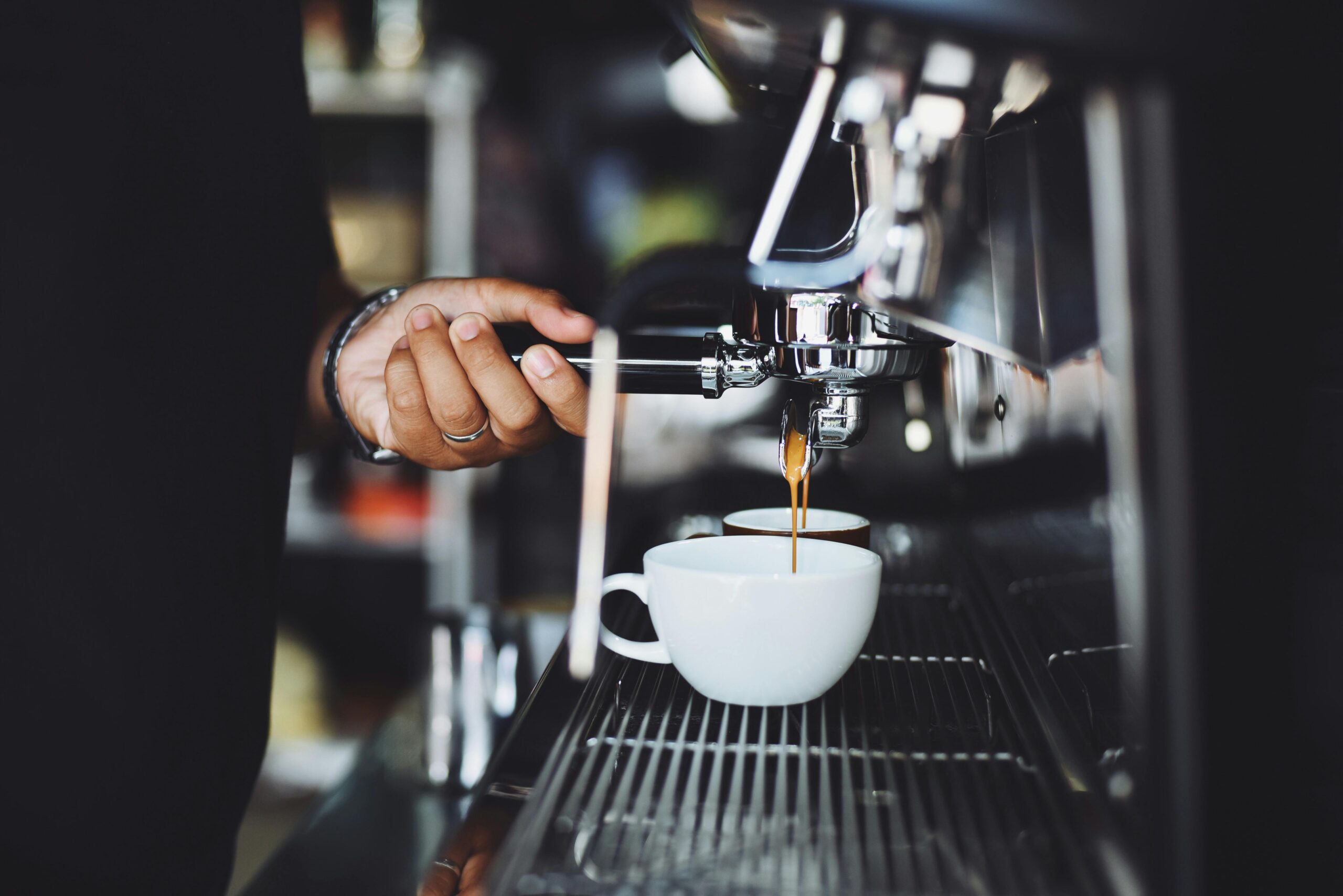 Close-up of a barista preparing espresso in a café using a machine