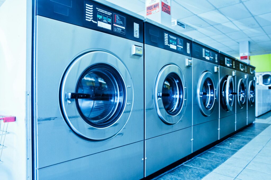 Interior of a contemporary launderette featuring advanced stainless steel washing machines.